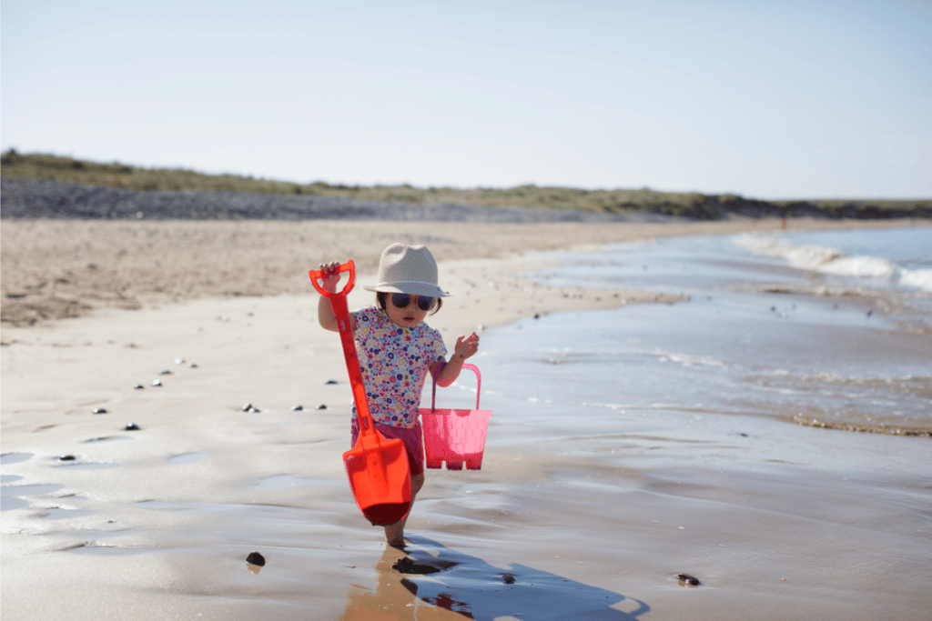 Tout-petit sur la plage portant des lunettes de soleil et un chapeau