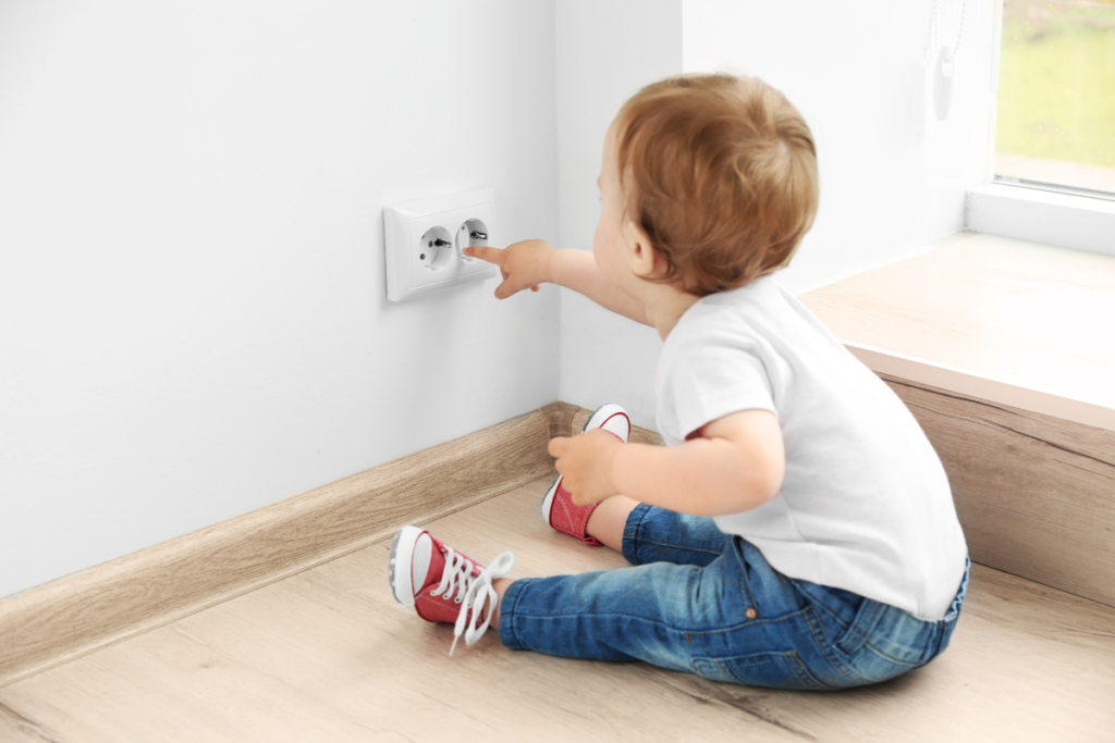 Jeune enfant mettant ses mains dans une prise électrique